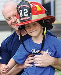 Firefighter Daniel Sanders shows Elijah Williams safety equipment.