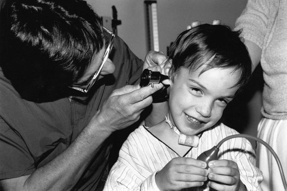 Robin Cotton, MD, examines Bernardo Tamez, who came from Mexico for tracheal reconstruction in 1989.