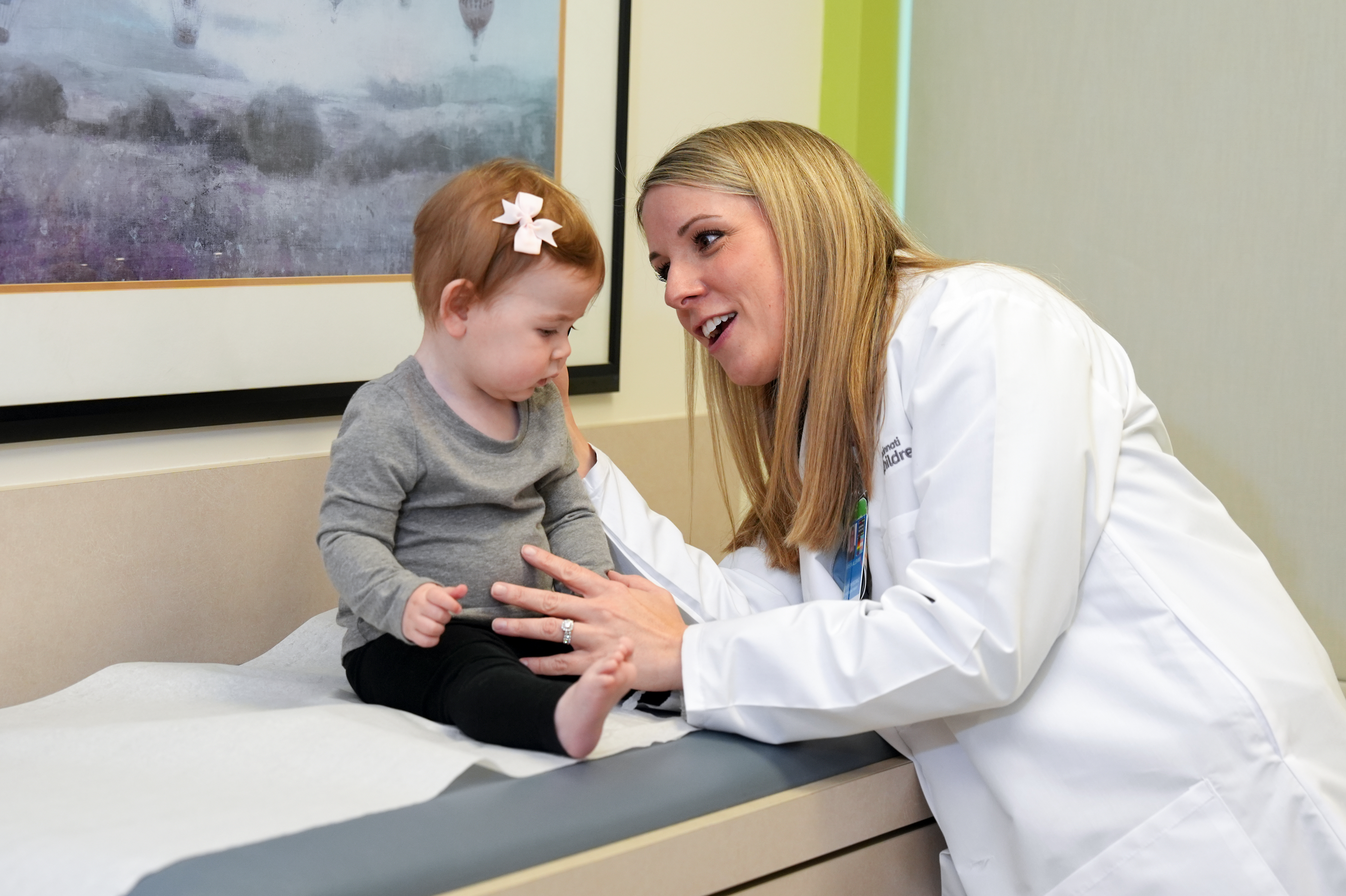 A smiling doctor examines a baby.