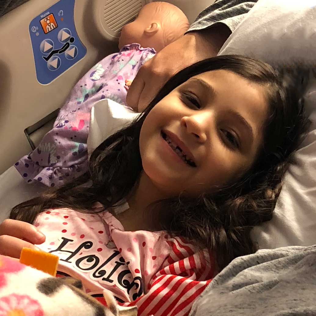 A little girl smiles in her hospital room. 