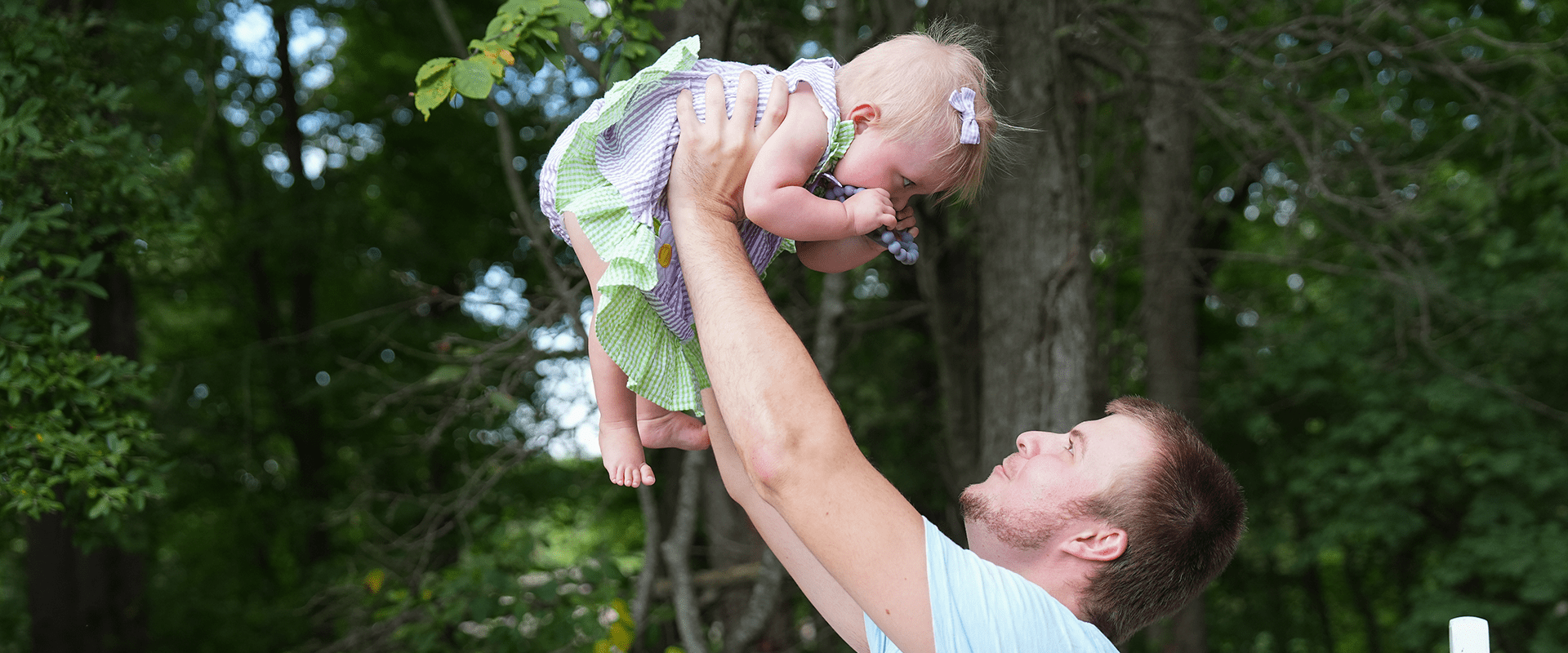 A father lifts his daughter into the air.
