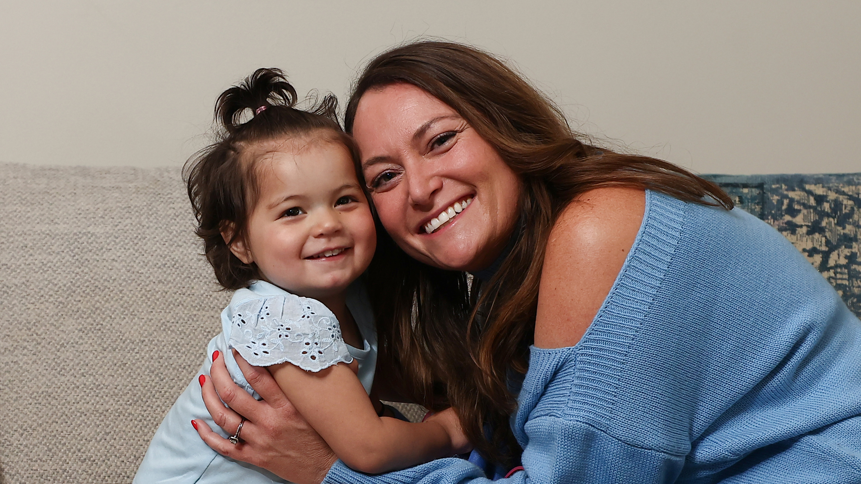 A little girl and her mother hug and smile.