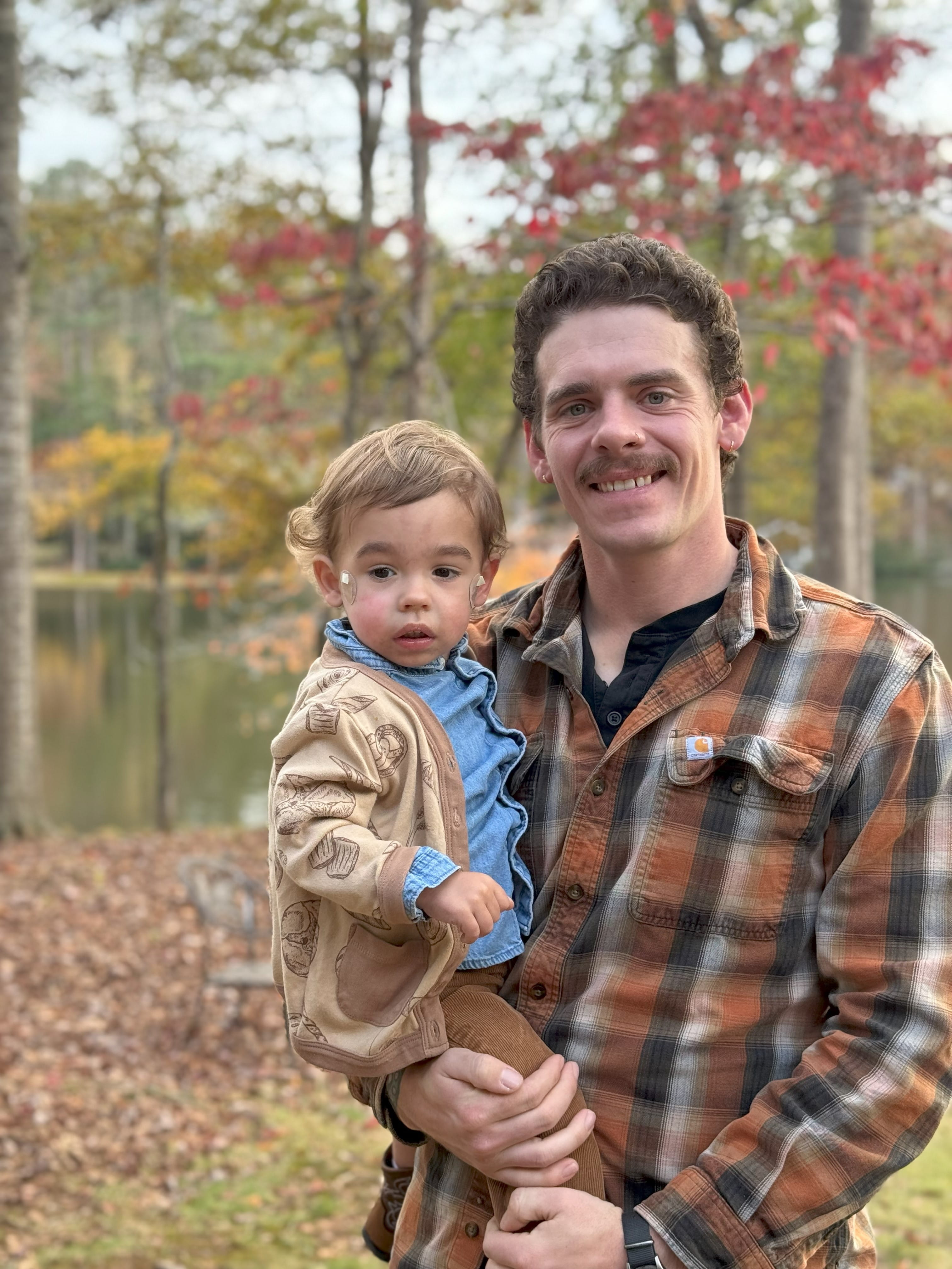 A little boy and his father outdoors on a fall day. 
