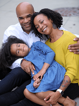 An image of a family smiling outside.