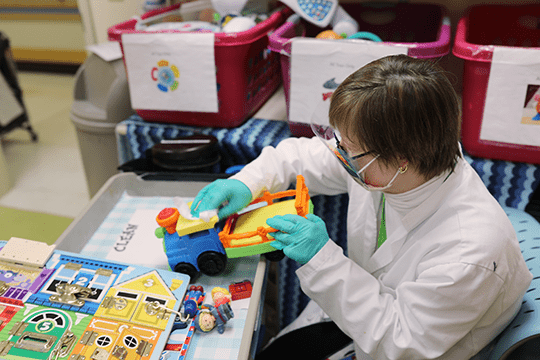 A Project SEARCH participant helps clean toys.