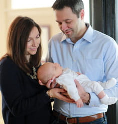 Husband and wife hold newborn baby.