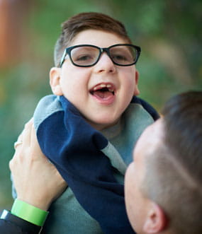 Boy smiling in dad's arms. 