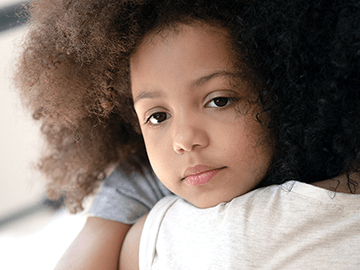 A mother holds her child over her shoulder.