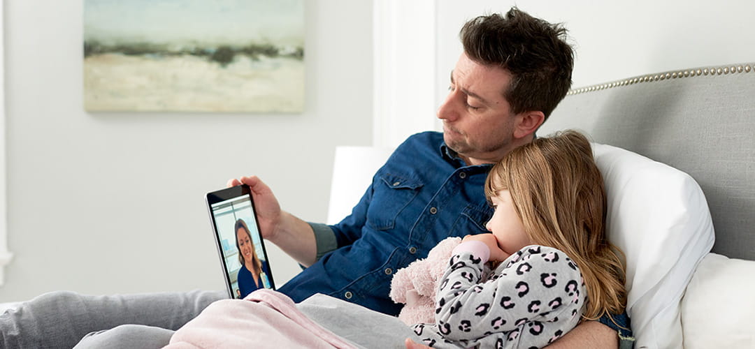 A photo of a father and daughter on a telehealth call.