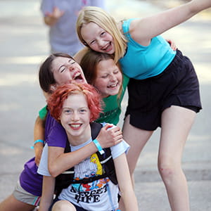 A photo of four tweens laughing and hugging.