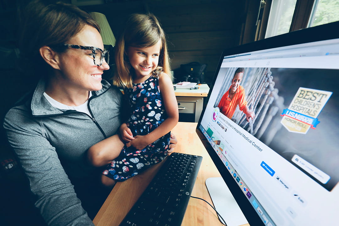 A photo of a mom and daughter looking at a computer screen together.