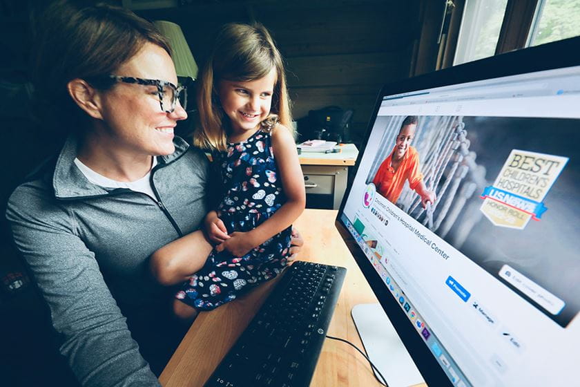 A photo of a mom and daughter looking at a computer screen together.