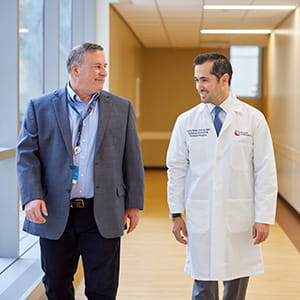 A photo of two men walking and talking.