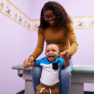A photo of a smiling baby with his mom.