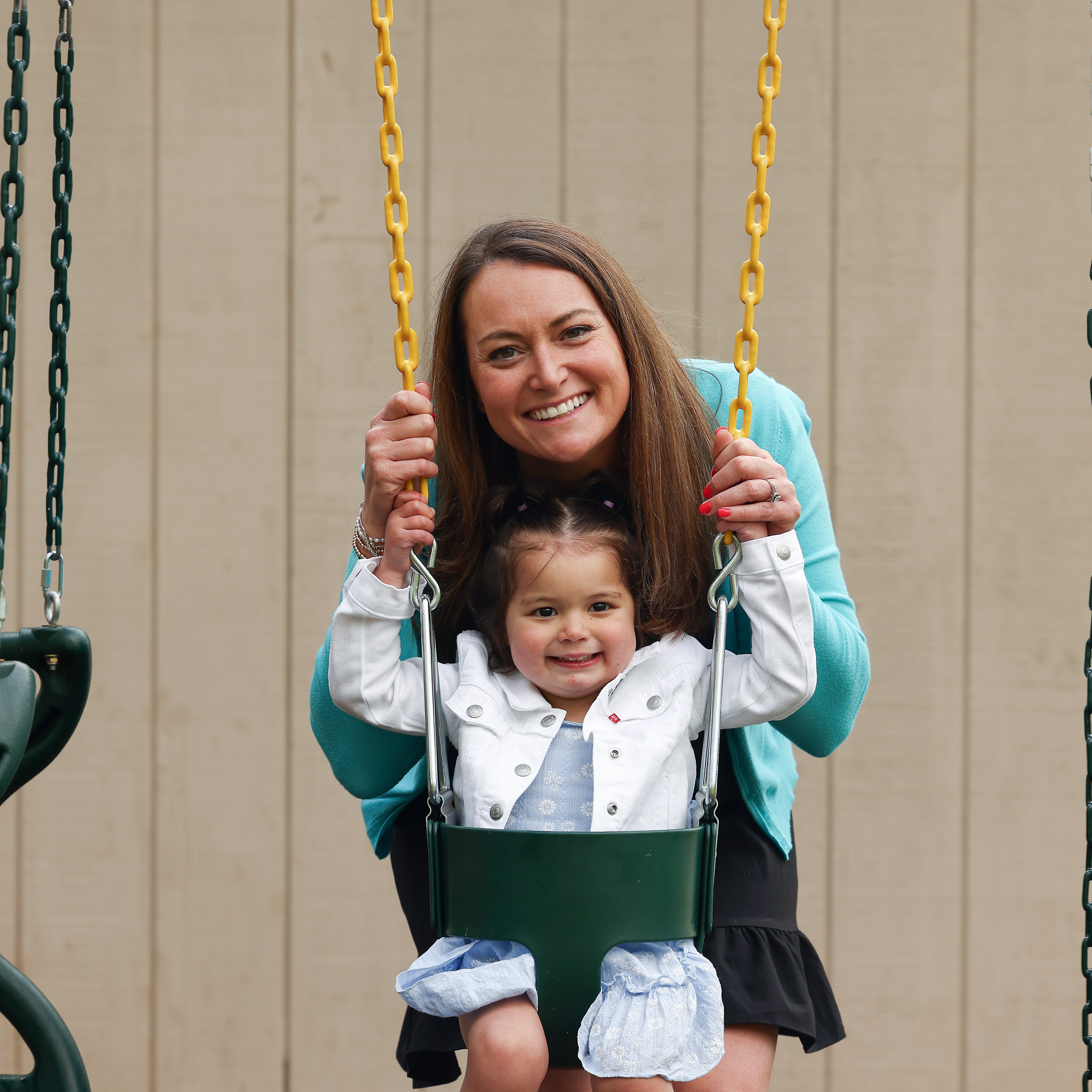 Kelly pushes her daughter Raegan on a swing. Raegan is a Neuroblastoma Program patient.