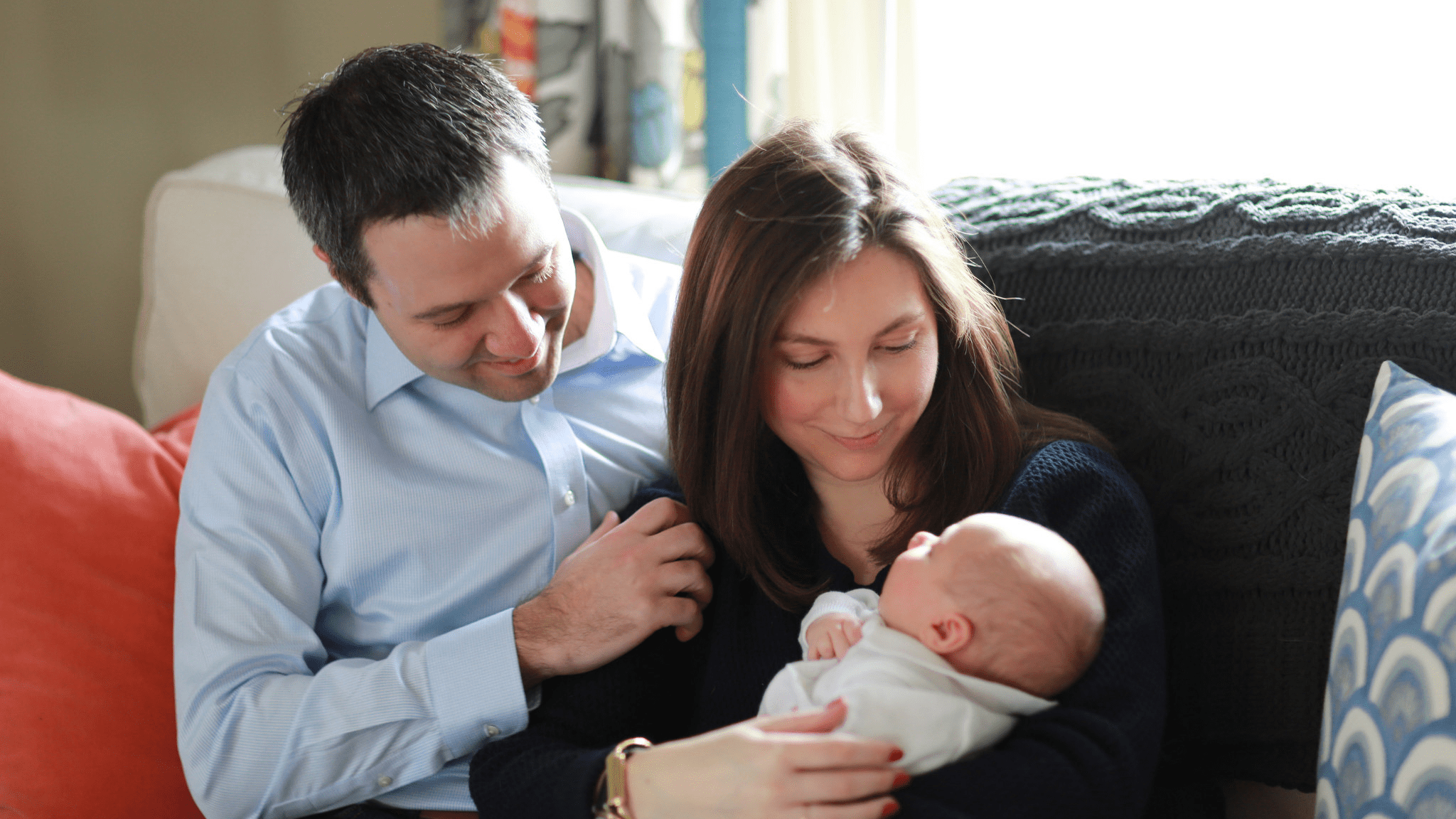 Parents holding their baby at home.