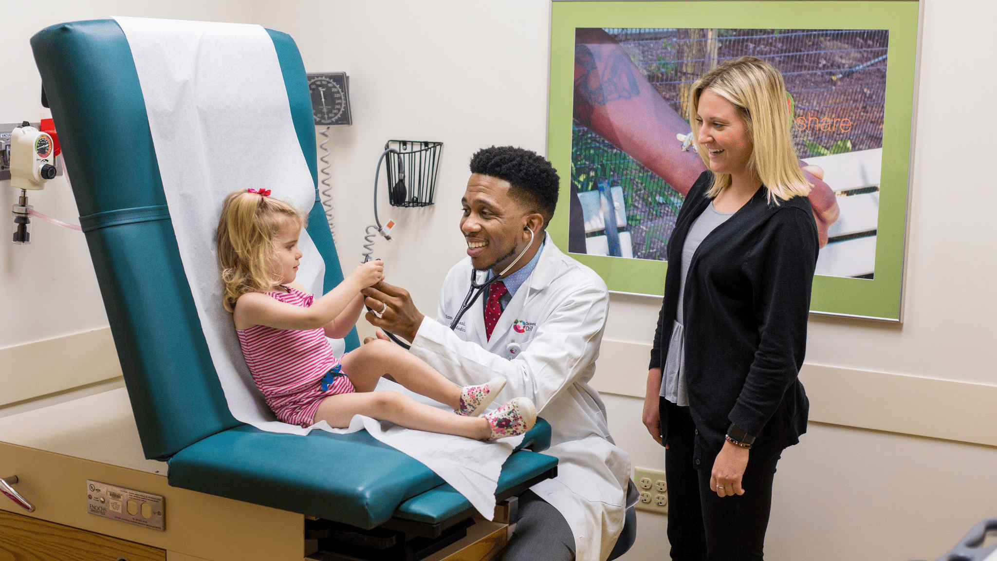 A smiling doctor examines a patient.