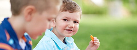 Two boys snacking on vegetables.