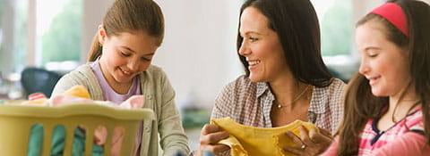 A woman and two girls folding laundry.