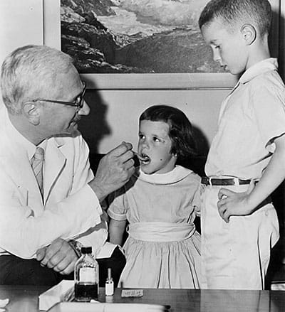 Dr. Albert Sabin gives a spoonful of medicine -- the oral polio vaccine.