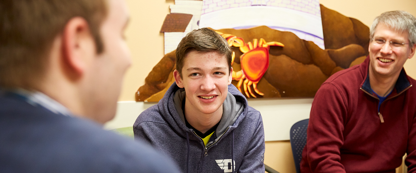 A patient and his dad speak with a doctor.