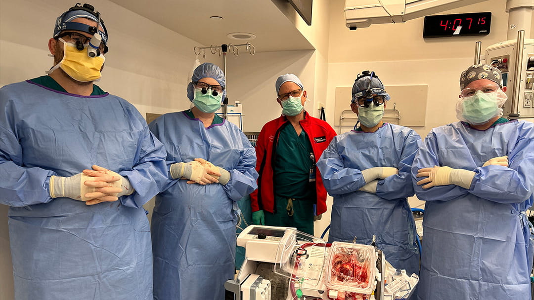 A surgical team posing next to the Organ Care System (OCS) Heart System.
