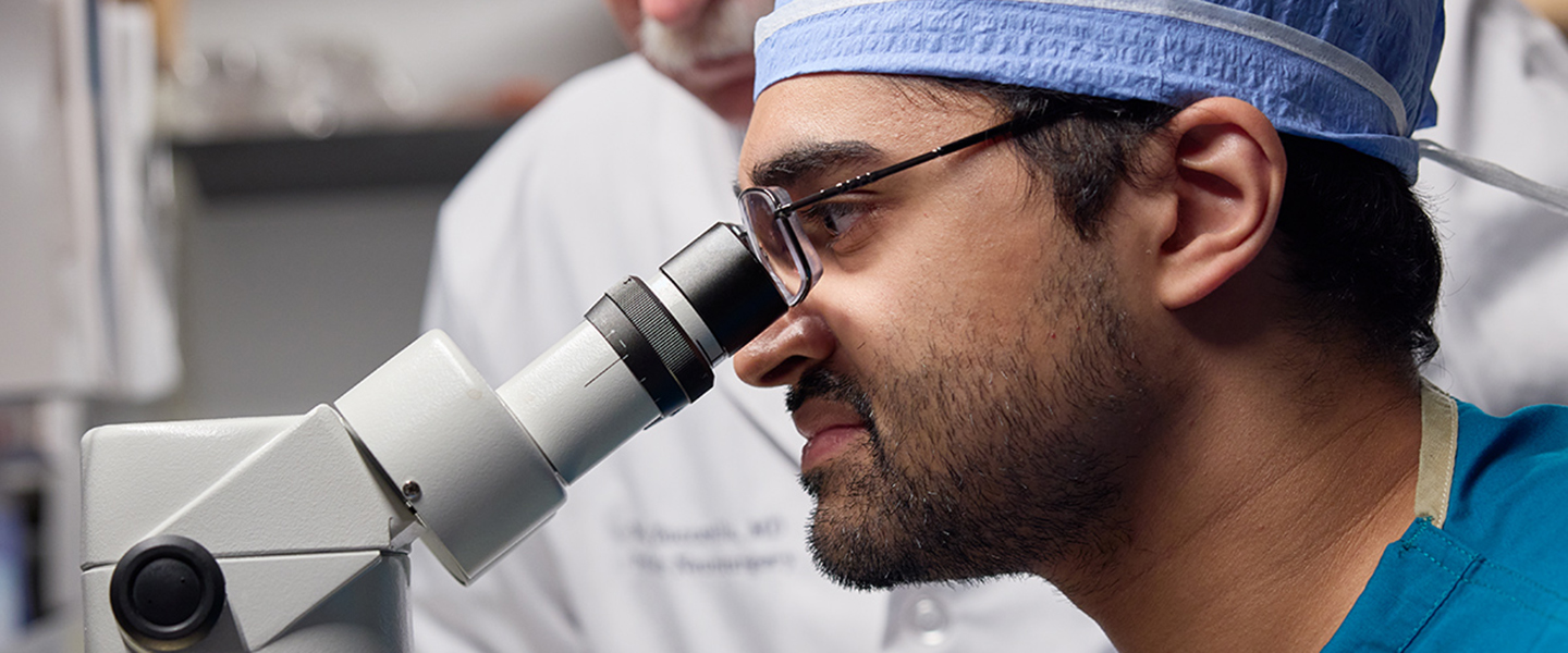 Photo of a doctor looking into a microscope.