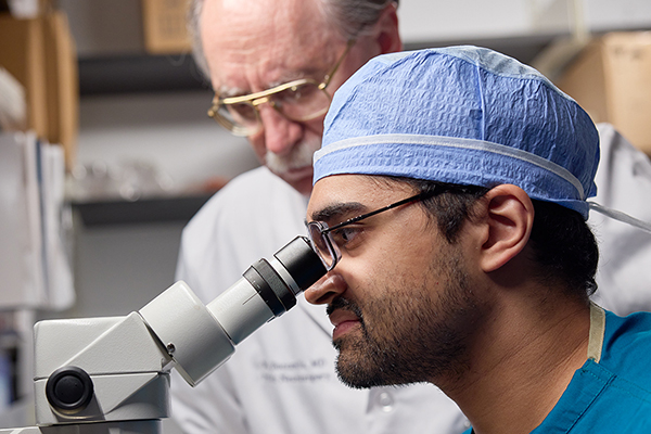 Photo of a doctor looking into a microscope.