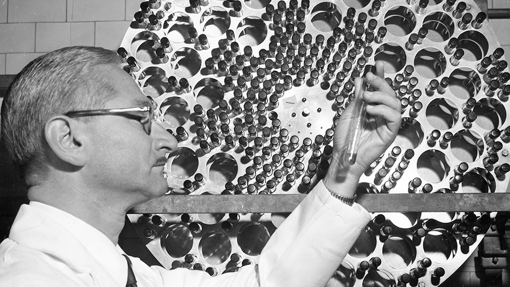 Black and white photo of a doctor holding up a test tube.