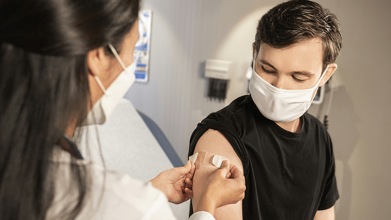 Nurse putting bandage on patient's arm.