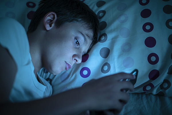 Child using cell phone in the dark.