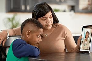 An image of a mother and her son using telehealth.