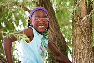 A smiling girl sitting in a tree.