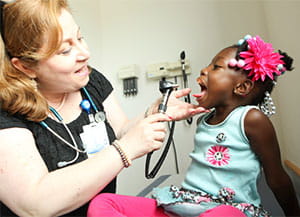 A doctor examines a young girl's throat.