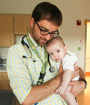 A doctor holding an infant.