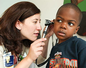 A doctor examines a young boy's ear.