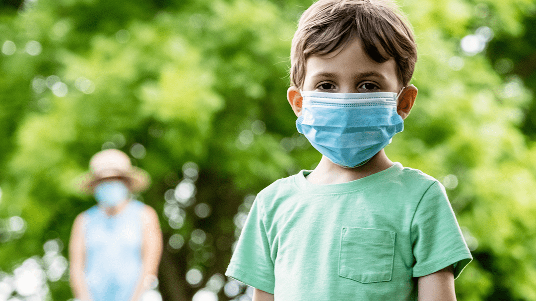 An image of a boy outside wearing a mask.