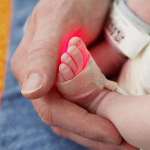 Image of a newborn's foot and a caregiver's hand.