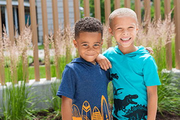 An image of two siblings smiling outside.