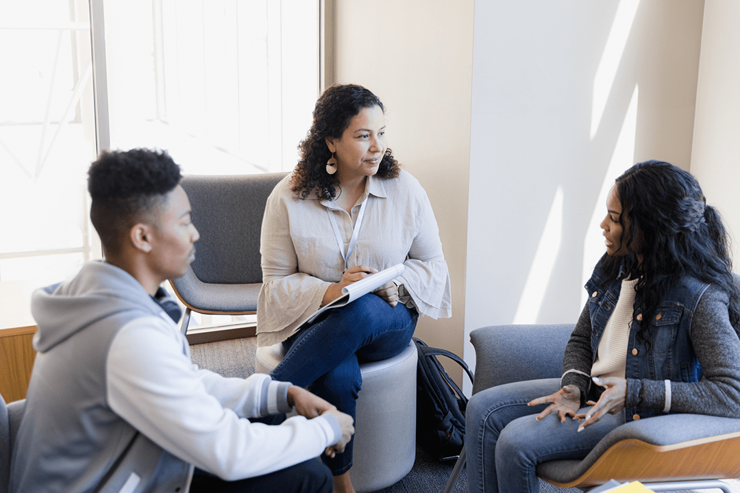 Three people talking inside.