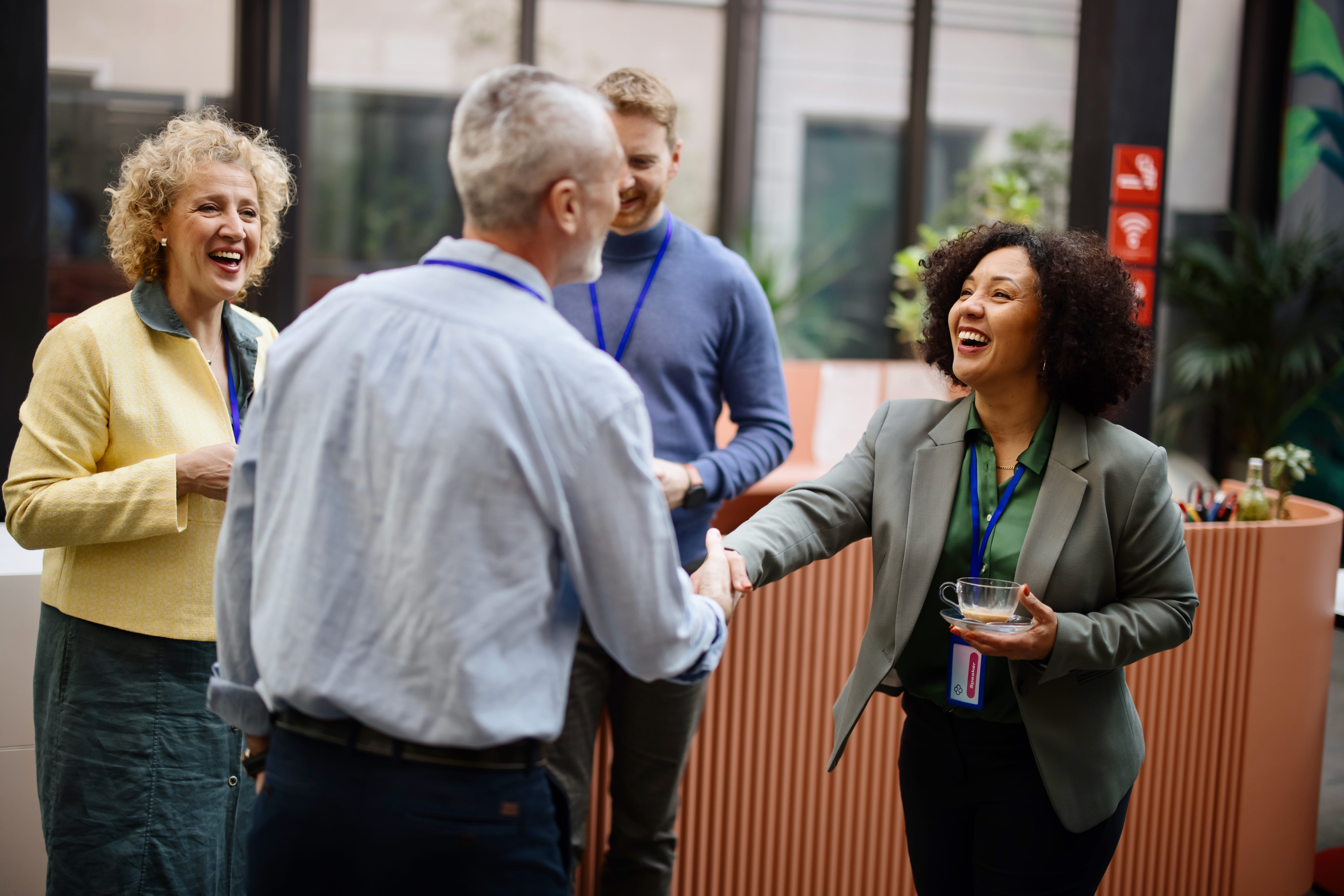 Businessperson shares a friendly handshake with another businessperson at a conference.
