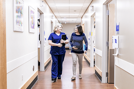 A photo of a pregnant patient who has CHD walking with her caregiver.