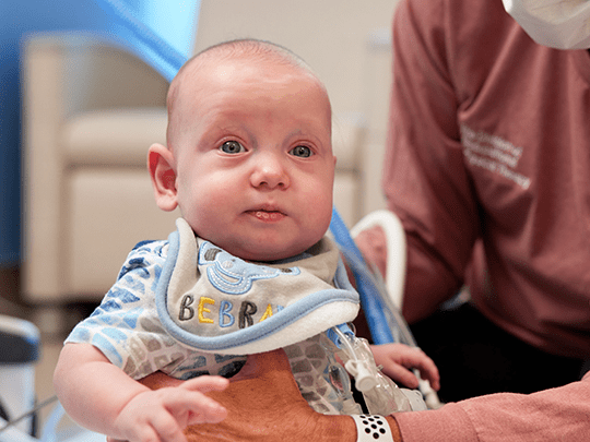A happy child being held by a nurse.