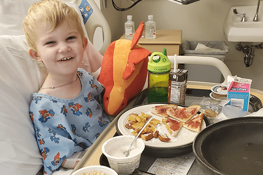 Levi smiles while eating in the hospital.