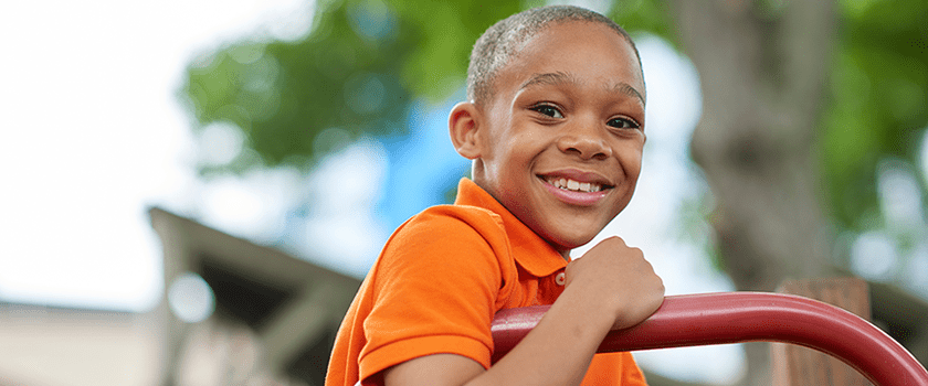 An image of a boy smiling while playing outside.