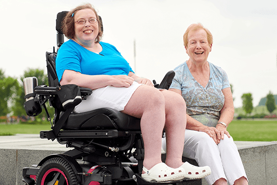 A spina bifida patient sitting outside with her mom.