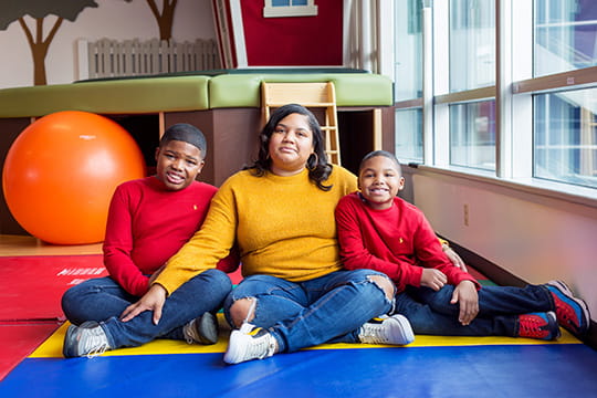 An image of two boys smiling with their mom.