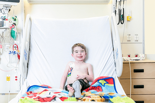 A young male dialysis patient sitting in a hospital bed.