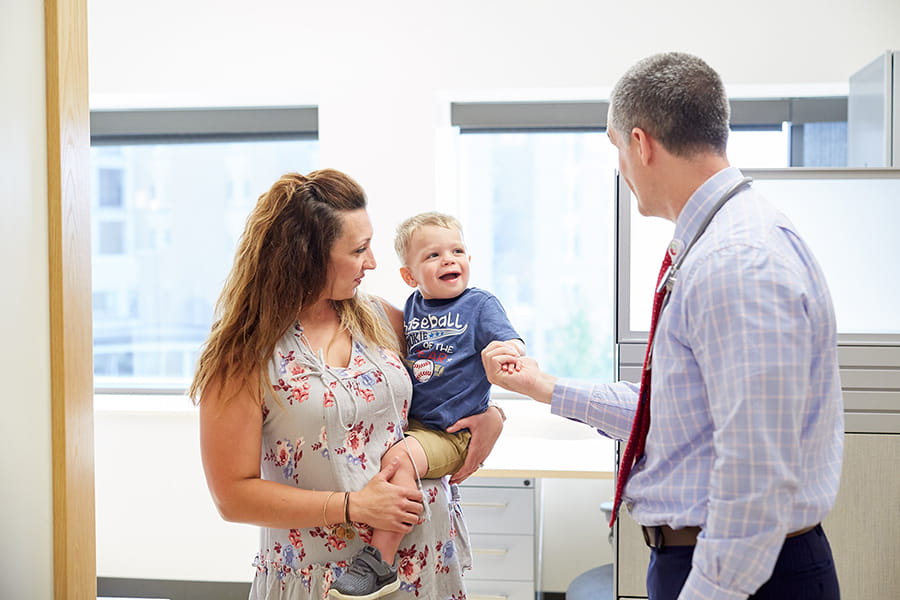 A parent and young child greeting a caregiver.