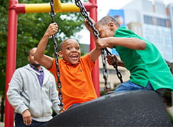 Two boys on a tire swing.